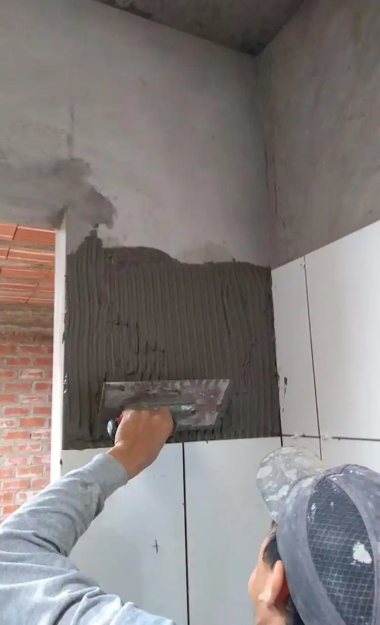 Albanil enchapando pared de baño 